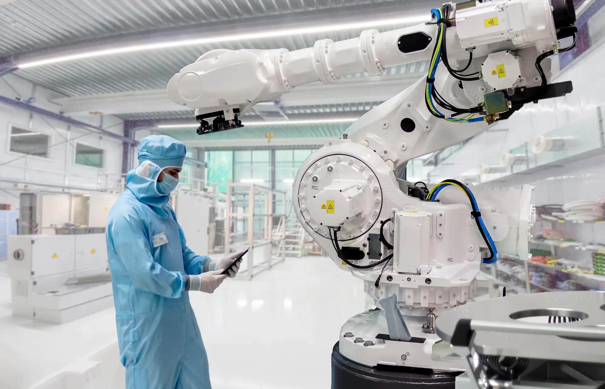 Engineer working alongside a robotic arm in a cleanroom