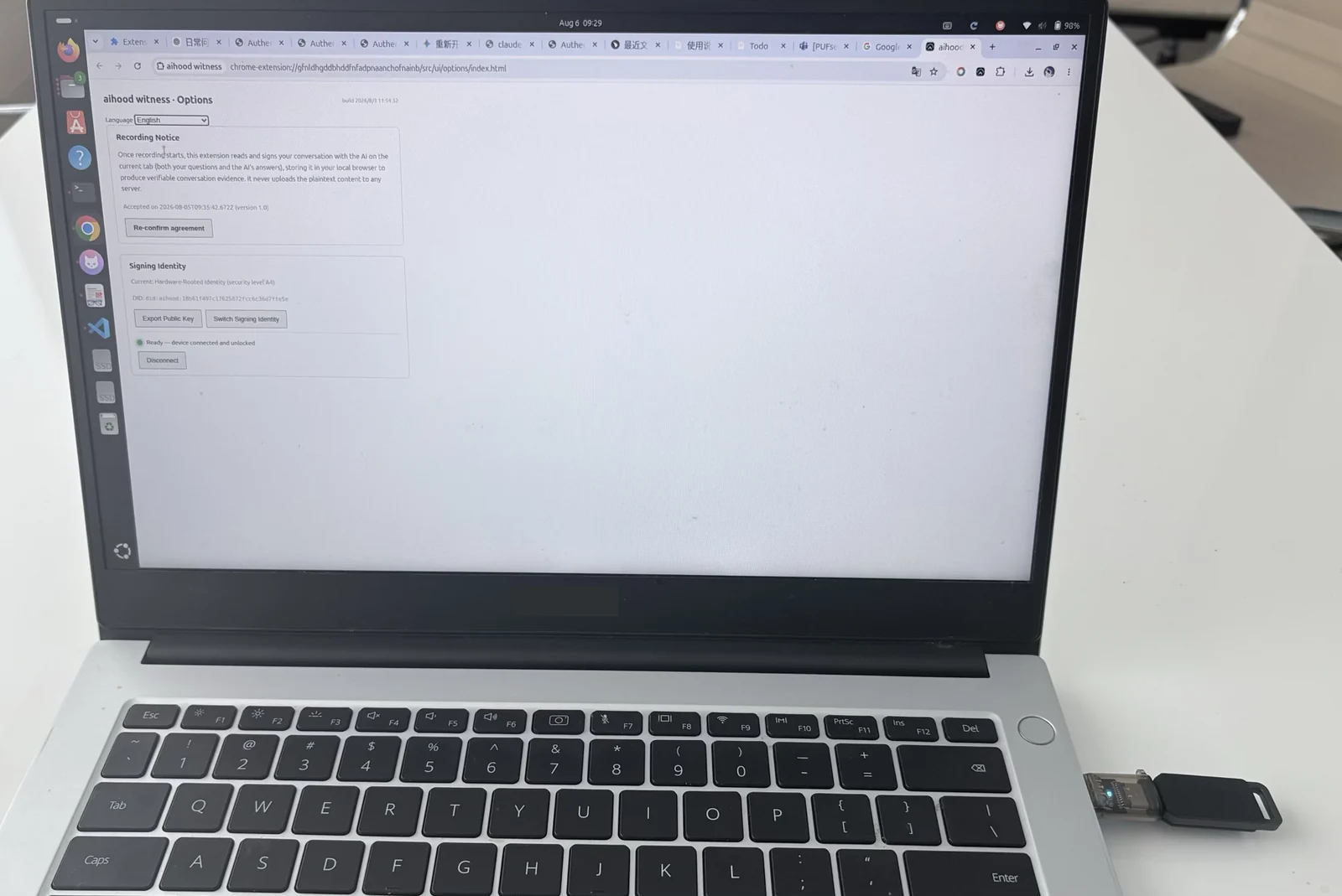A laptop showing the witness options page with a hardware signing key plugged into a USB port